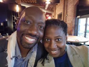 Ray and Natasha Weefaa, founders of Naked and Rich, smiling together in a portrait promoting their Financial Oneness couples card game.