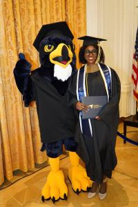 A proud graduate from the Class of 2025 stands with Cali the Falcon, marking the mascot’s first commencement appearance.