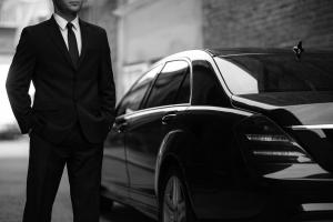 Professional chauffeur standing beside a luxury black car, representing premium black car and chauffeur service in San Diego by Richline Transportation.