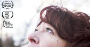 Close-up portrait of Clara Berta looking upward, with film festival laurels displayed beside her.