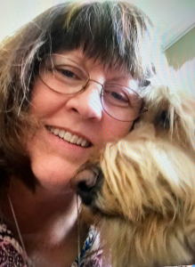 Bonnie Rauh smiling with the family dog, whose resilience and warmth feature in Randy Rauh’s memoir.