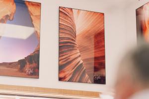 Wall-mounted fine-art prints by Navajo photographer Lionel Bigthumb, featuring Antelope Canyon formations and warm desert tones inside a gallery setting.
