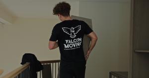 Professional Falcon Moving mover carrying furniture in Atlanta home wearing company branded shirt