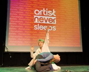 Dancers performing a choreographed routine under stage lighting at the Startizta showcase.