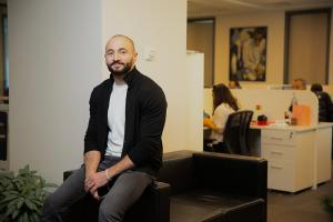 Rashad Mirzayev sitting on the ede of a chair in an office.