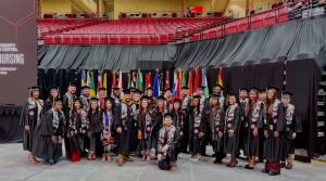 male and female students in caps and gowns pose for a photo