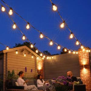 Friends relaxing under warm outdoor string lights in a cozy backyard at night