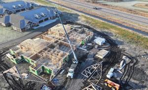 Aerial view of townhomes under construction in an HOA community, highlighting residential development with garage-focused home design.