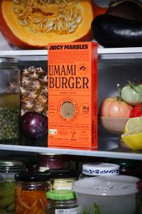 Known for hyper-realistic plant-based whole cuts, Juicy Marbles today launches Umami Burger, a new high-protein veggie patty with a more whole-food-forward ingredients list A lone Umami Burger perches patiently on the edge of a fridge shelf.