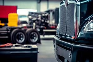 Late-model semi truck inside a professional diesel repair shop with service equipment and tool stations visible