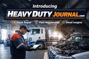 HeavyDutyJournal.com launch image showing a diesel technician diagnosing a heavy-duty truck in a professional repair shop environment.