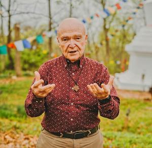 Older man shown with Tibetan prayer flags in background