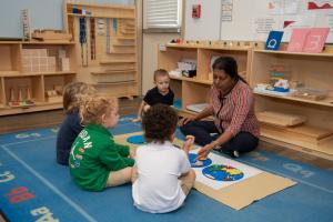 Edquisitive Montessori educator guides children through hands-on learning activity