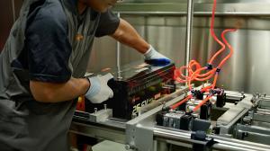LiThink today published a public overview of its internal “11-Point Lab Protocol” used to validate LiFePO₄ batteries designed for RV, marine and off-grid applications in Europe A technician in a grey LiThink uniform positions a black 25.6V 100Ah LiFePO4 battery on an industrial testing rig featuring red pneumatic hoses for quality control and mechanical stability testing.
