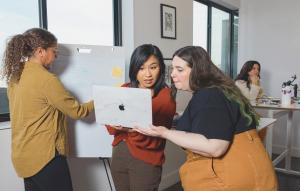 Creative professionals collaborating around a laptop and whiteboard during a brand strategy and digital planning session at Creative Repute.