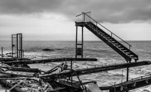 Black and white Image of a brunt staircase leading to nowhere over the Pacific Ocean.