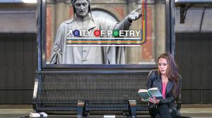 Person reading on a Philadelphia subway platform beneath the City of Poetry public art installation, illustrating how local culture and storytelling can benefit from increased global visibility ahead of the upcoming global events.