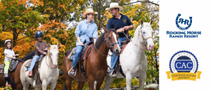 A group of four individuals, including two children, riding horses in a colorful autumn setting at Rocking Horse Ranch Resort.