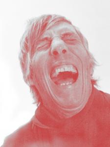 Todd Collins as photographed by Actor/Photographer, Billy Zane with a Leica D-Lux 7 in grey and red tones. The image shows a man laughing and is part of Billy Zane's new gallery exhibition, 