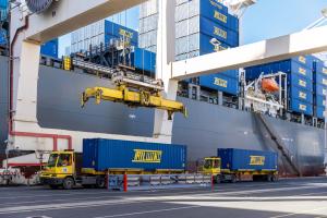 Blue shipping containers branded Tailwind being unloaded from a ship