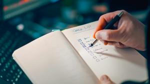 Close-up of a hand marking a checklist in a notebook, symbolizing structured breach-notification workflows.