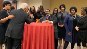 Group of adults gathered around a table in conversation during a community meeting or discussion.