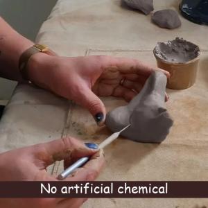 Hands shaping pottery clay with a sculpting tool during a process of molding and detailing by hand.