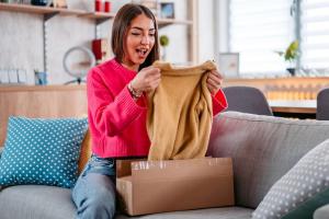 Lady wearing a pink sweater opening a parcel.