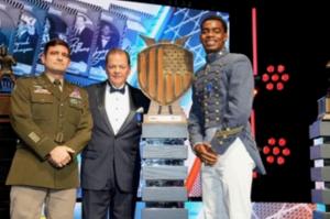 Thomas "Rick" Hughes, CEO of Capital Group of Companies and Lieutenant Colonel Special Forces TJ Fera present the 2025 Defender of the Nation Award to Kouri Crum of Virginia Military Institute at the Bronko Nagurski Awards dinner in Charlotte, NC.
