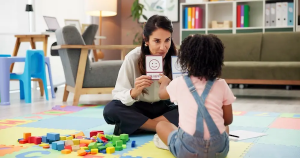 Clinician using visual emotion cards during a play-based ABA therapy session with a young child at Bierman Autism Centers.