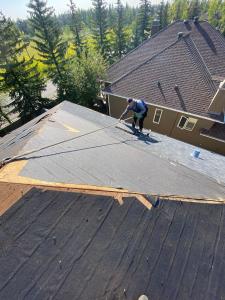 Kole Perkeqi owner of Vami Roof Repair, harnessed and stripping a roof in Calgary