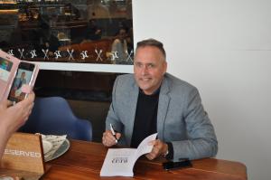 Paul Rushworth-Brown signing copies of his novel Outback Odyssey at a book signing event.
