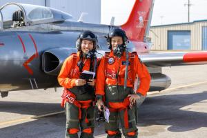 Student and Instructor in orange flight suits with aircraft at London International Airport