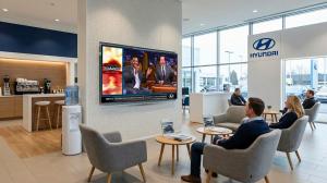 The Digital Dealership System customer lounge TV inside a Hyundai dealership with guests seated enjoying family friendly entertainment on a large wall-mounted TV.