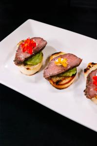 Peppered beef tenderloin crostini with chimichurri-style sauce and colorful pepper garnish, featured as part of Chef Serge Krikorian's winter appetizer demonstration on THV11's The Vine. Photo by Vibrant Occasions Catering.