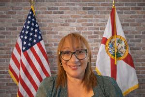 Evelyn seated with the American flag and Florida flag behind her,