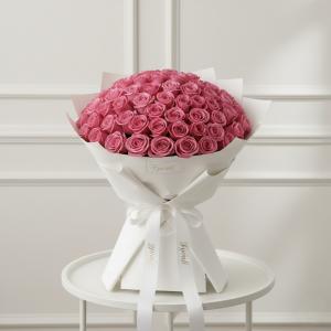 Fyonlli Expands Online Flower Delivery and Gifting Services across the United Arab Emirates 15 A large bouquet of vibrant pink roses is elegantly arranged in white wrapping and tied with a ribbon, placed on a round table. The setting feels luxurious and romantic.