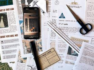 Top-down photo of The Green Star printable escape room components including mission files, scissors, and a smartphone app.