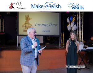 man wiht microphone and woman in blakc dress in front of stage to give out award