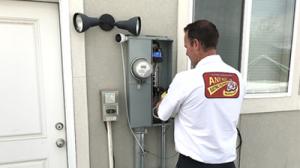 An Any Hour technician examining an electric panel.