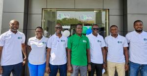 Group photo of the TGTS management team standing outside the company’s office entrance, wearing branded TGTS shirts, taken during a collaborative engagement related to a mutual partnership announcement.