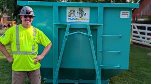 Trash Pandy owner William Shackelford standing next to a teal roll-off dumpster with company branding in Gallatin TN