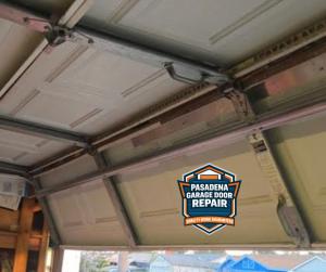 Interior view of a sectional garage door featuring metal hinges, tracks, and a center support bar, branded with the Pasadena Garage Door Repair 