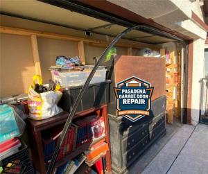 garage door track pulled away from the wall in a cluttered garage, showcasing a complex repair situation handled by Pasadena Garage Door Repair.