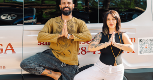 Saha Yoga Sedona founders holding tree pose in front of a branded yoga van in Sedona, Arizona.