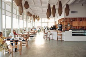 Spirit Origin coffee shop and From the Roots restaurant in Roatán, Honduras, featuring guests seated indoors with panoramic island views visible around the property.