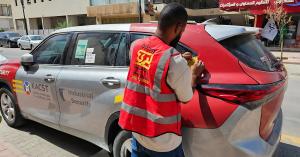 An installer applying a vinyl wrap on the rear panel of a car for KACST, showing the detailed application of vehicle branding in Riyadh.