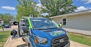 STL Window Cleaners service van parked at a St. Louis-area home while a technician cleans exterior windows with a water-fed pole.