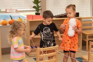 Edquisitive Montessori students practice fine motor skills with yarn in a curiosity-driven studio