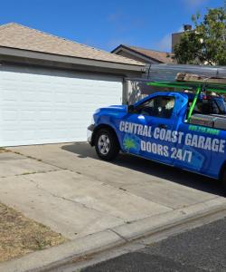 Professional technician installing a new residential garage door, securing panels and aligning tracks for smooth and reliable operation in San Luis Obispo County, California.
